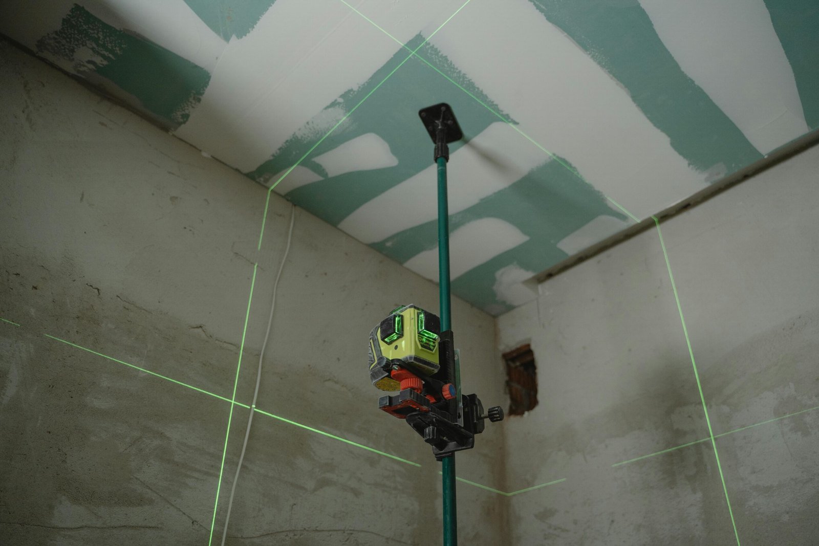 A laser level tool in action at an indoor construction site with marked walls.